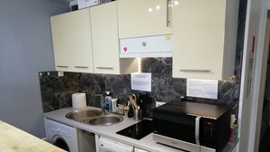 Una cocina compacta equipada con lavavajillas, pileta doble, microondas y cocina de tamaño reducido.