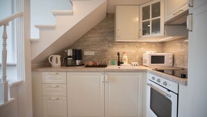 A kitchen with white cabinets, a microwave, an oven, and a coffee maker.