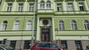 A multi-story building with a green facade, large windows, and a central entrance.