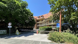 A courtyard with cobblestone pavement, a gated entrance, and a building with balconies.