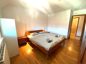 Ein Schlafzimmer mit einem hölzernen Bett, zwei Nachttischen und einem bei dem Bett stehenden Tisch.