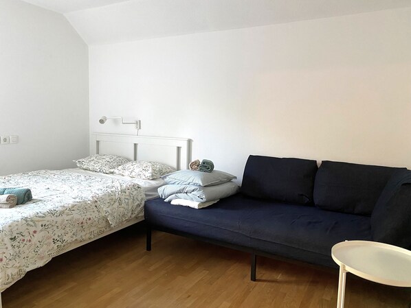 A bedroom with a bed, a sofa, and a small table. - Lovely Apartment just above the lake Bled (Bled)