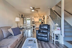 A spacious living room with a leather chair, a gray sofa, and a dining area in the background.