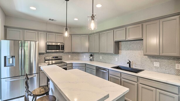 A modern kitchen with stainless steel appliances, a marble countertop, and pendant lighting. - Pet-Friendly Houston Townhome w/ Fenced Yard (Houston)