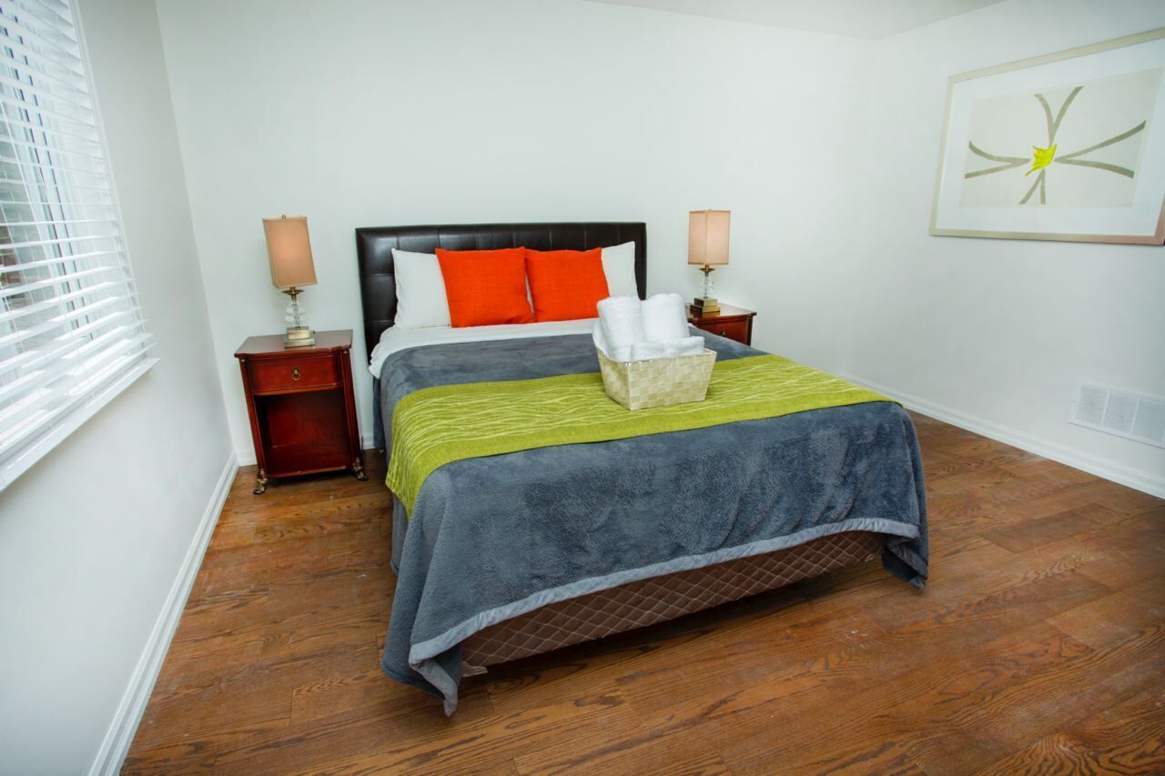 A neatly arranged bedroom with a large bed, two bedside tables, and a wall-mounted lamp.
