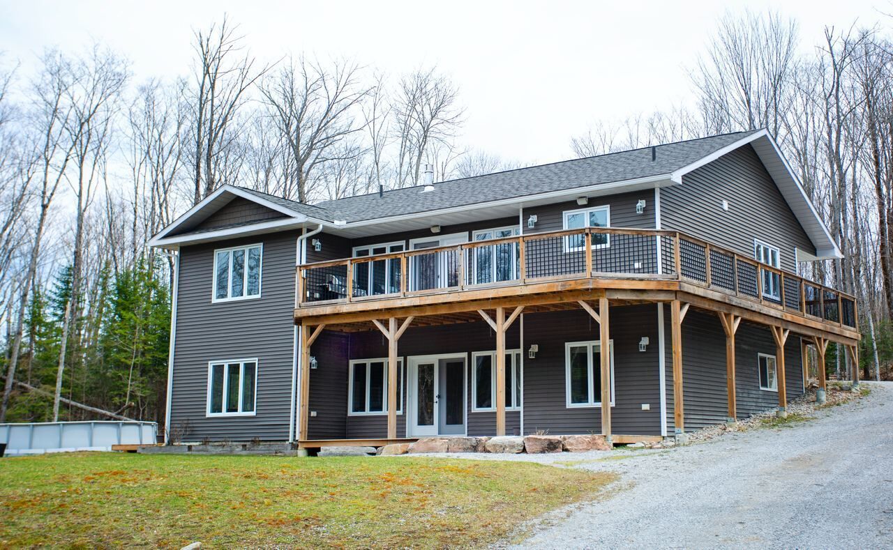 Une maison à deux étages avec un balcon, une véranda et un garage.