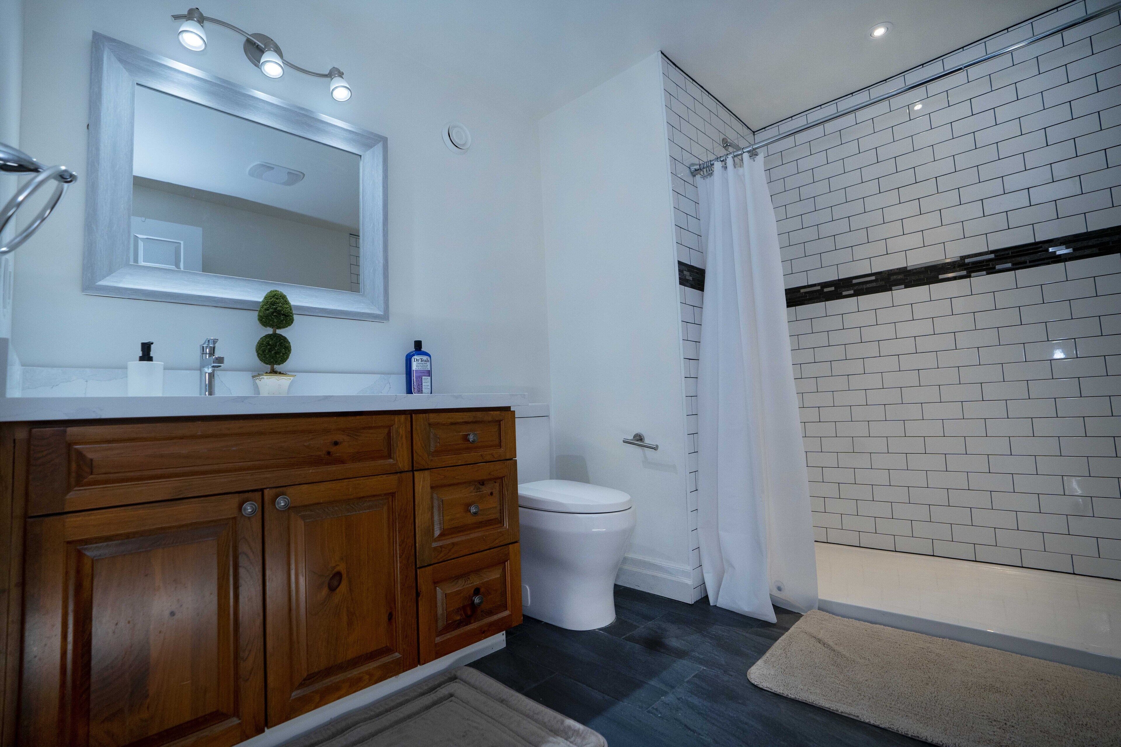 Un baño moderno con tocador de madera, inodoro blanco y cabina de ducha de vidrio.