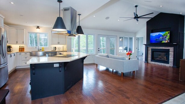A spacious kitchen with a large island, a fireplace, and a television. - Modern Mountain House in the Heart of Haliburton, Mins to Lake (Dysart et al)
