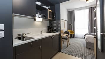 Una cocina moderna con estufa integrada, cafetera y microondas. Cuenta con un pequeño comedor con una mesa y sillas.