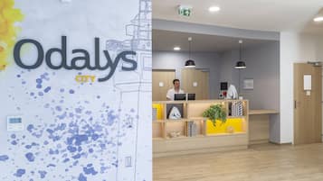 Una recepción con diseño moderno, una pantalla digital y una planta en maceta.