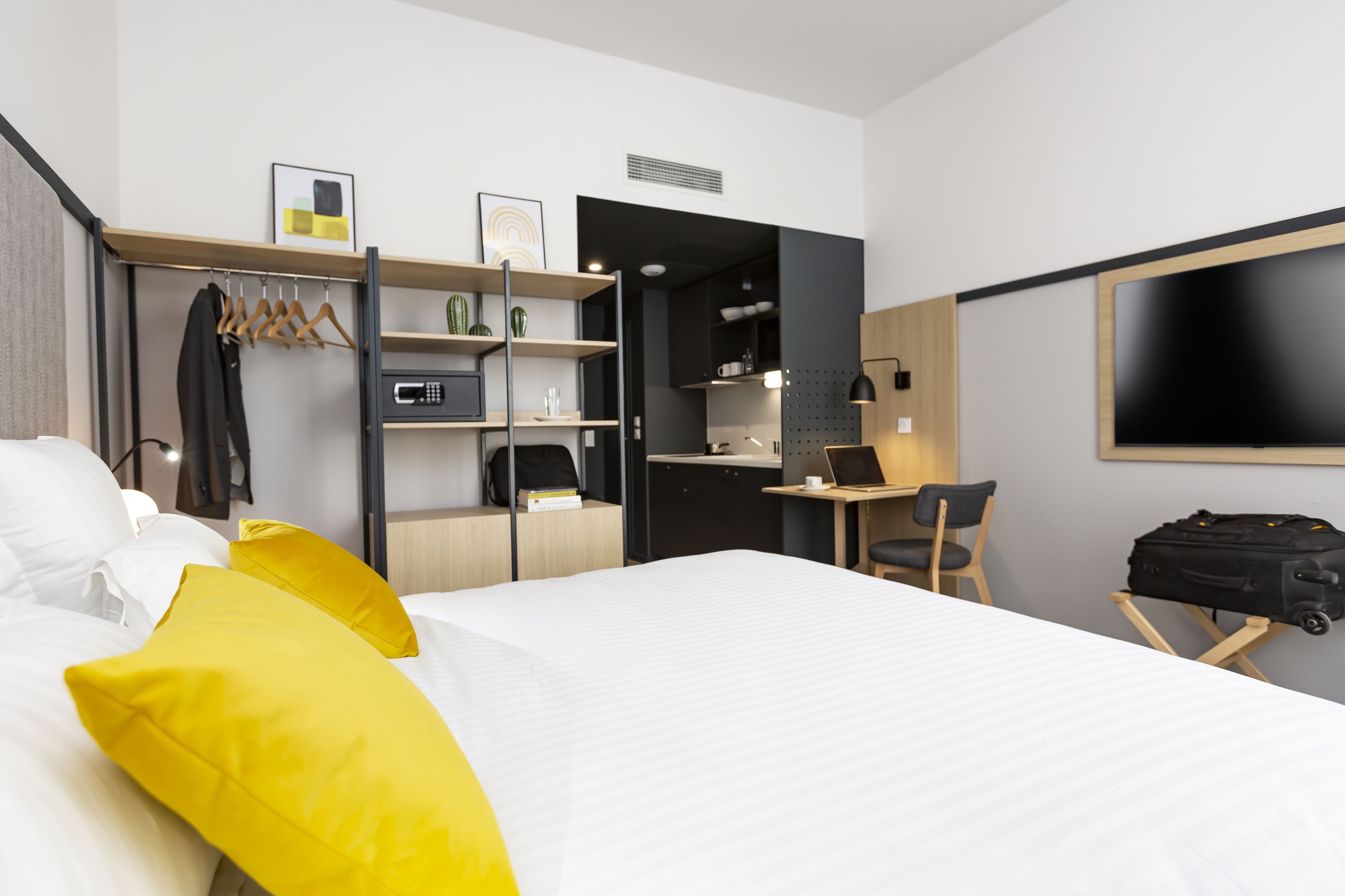 Una habitación de hotel con cama, escritorio, silla y televisor.