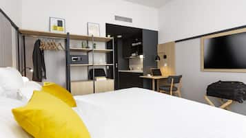 Una habitación de hotel con cama, escritorio, silla y televisor.
