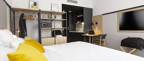 A hotel room with a bed, a desk, a chair, and a TV.
