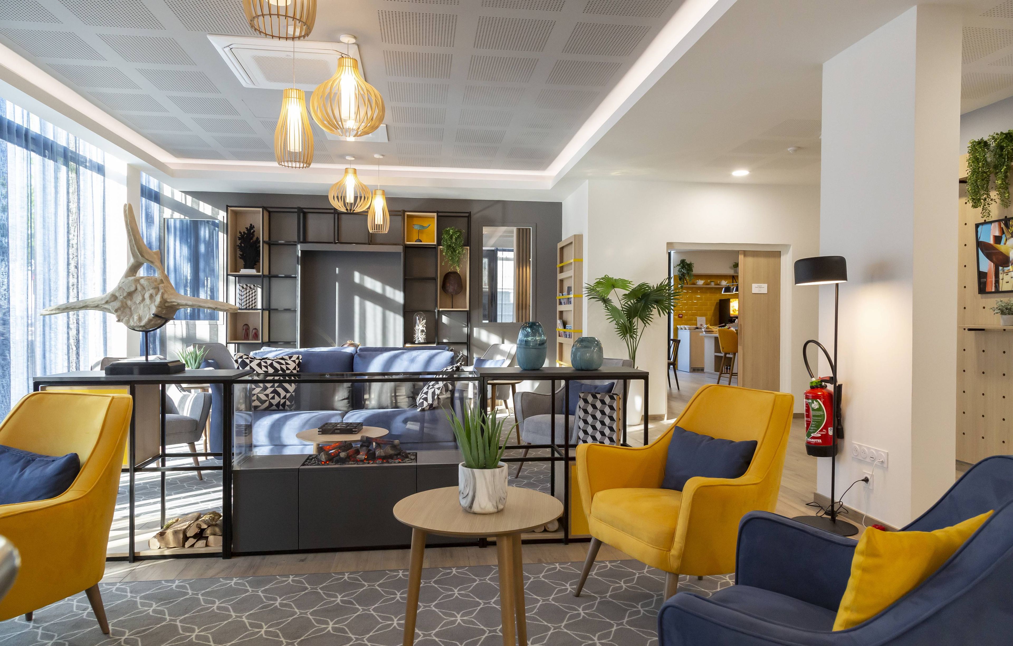A modern living area with a sofa, yellow chairs, a coffee table, and a kitchen in the background.