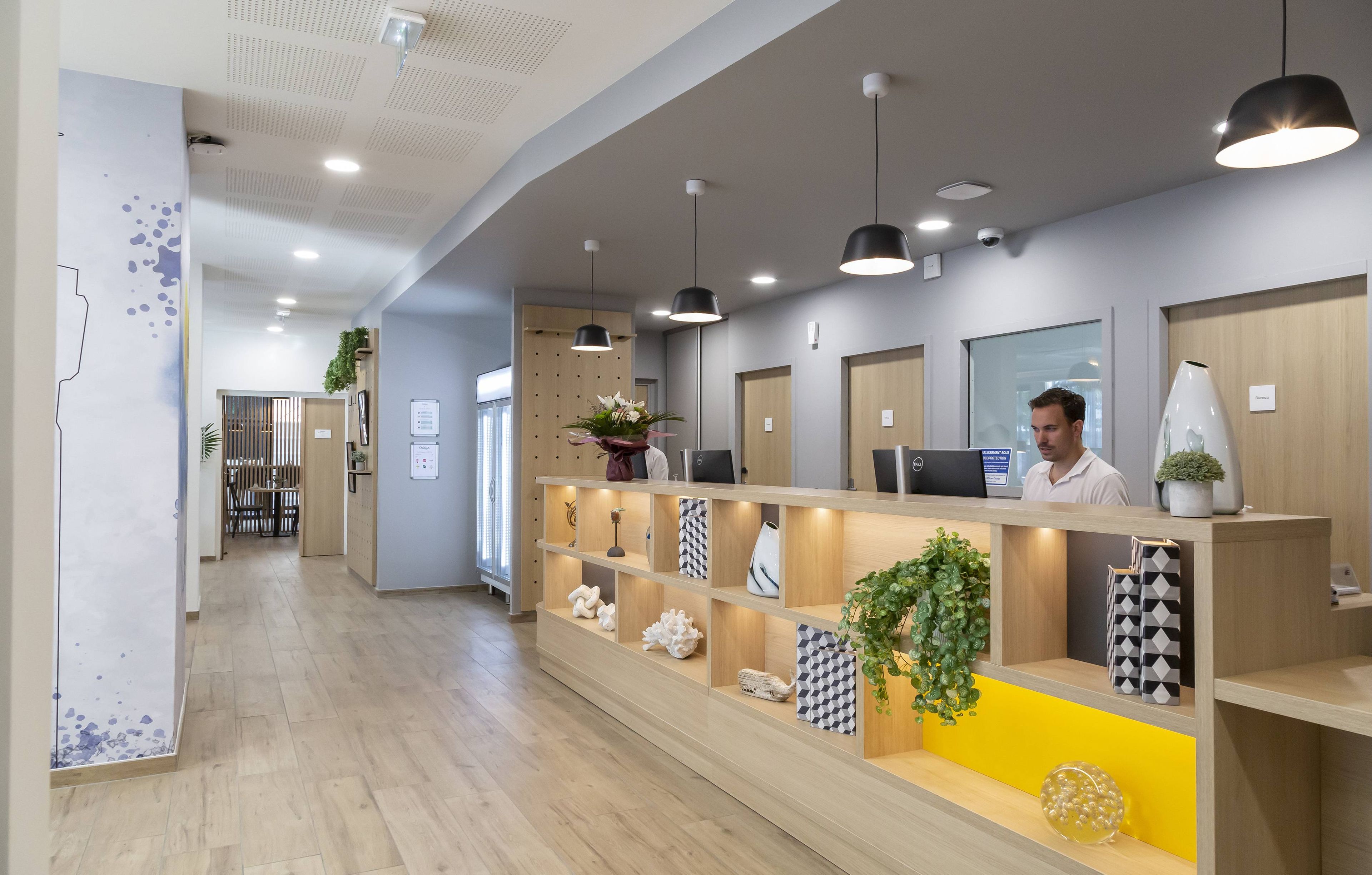 A reception area with a wooden reception desk, multiple pendant lights, and shelves with decorative items.