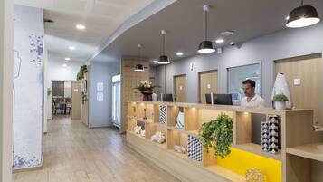 A reception area with a wooden reception desk, multiple pendant lights, and shelves with decorative items.