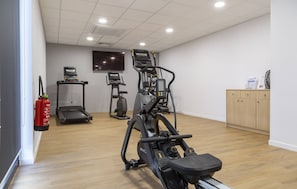 Ein Fitnessstudio mit Laufbändern, Crosstrainern und einem Ergometer.