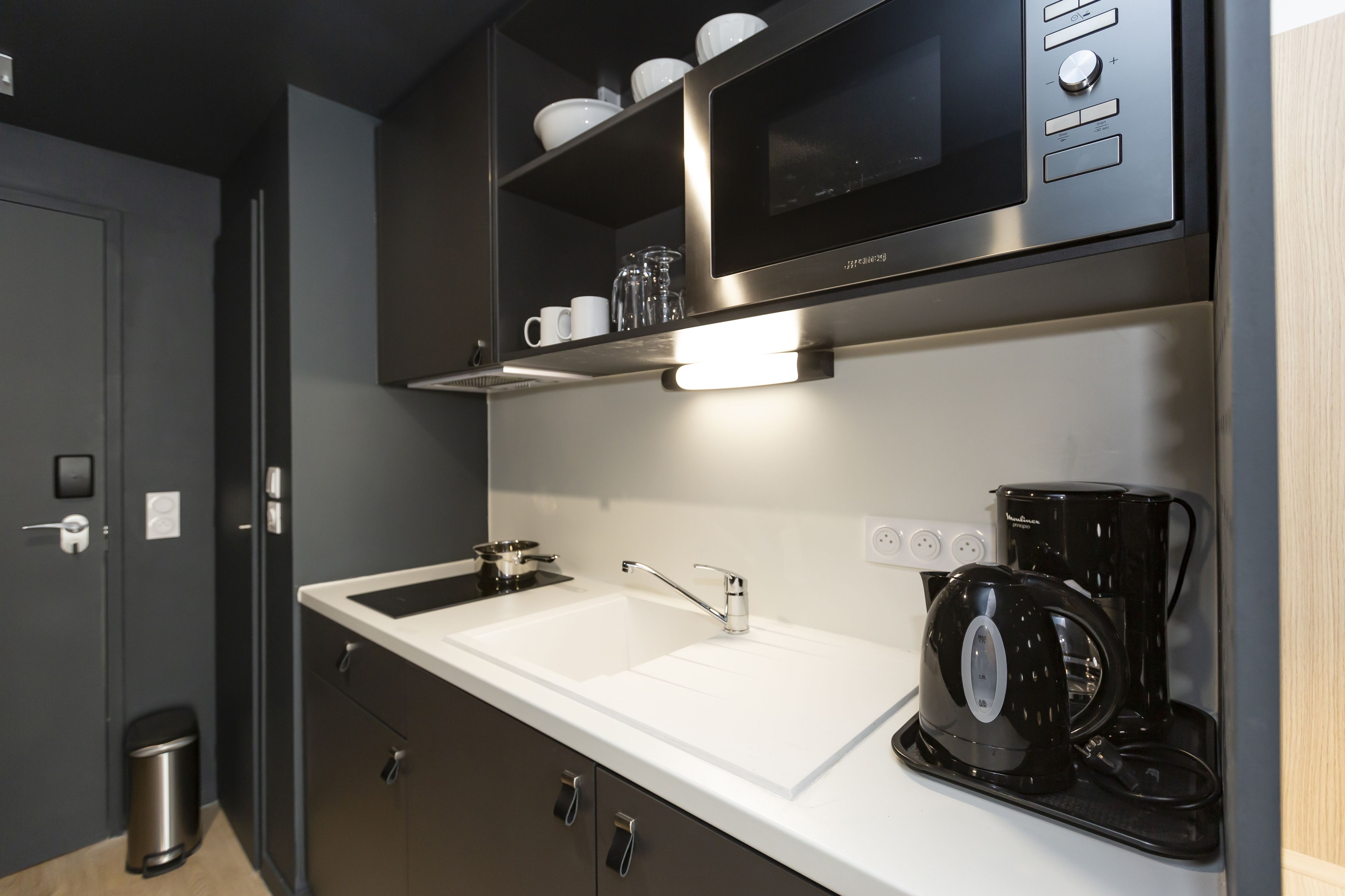 Una cocina moderna con microondas integrado, cafetera y lavabo.