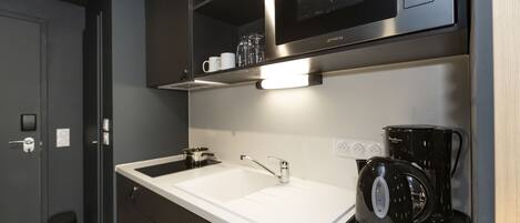 Una cocina moderna con microondas integrado, cafetera y lavabo.