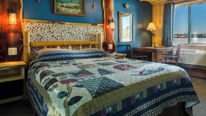 Una cama con colcha, cabecera de madera y ventana con vistas.