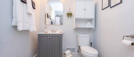 Un baño con tocador gris, inodoro blanco y baldosas de suelo estampadas.