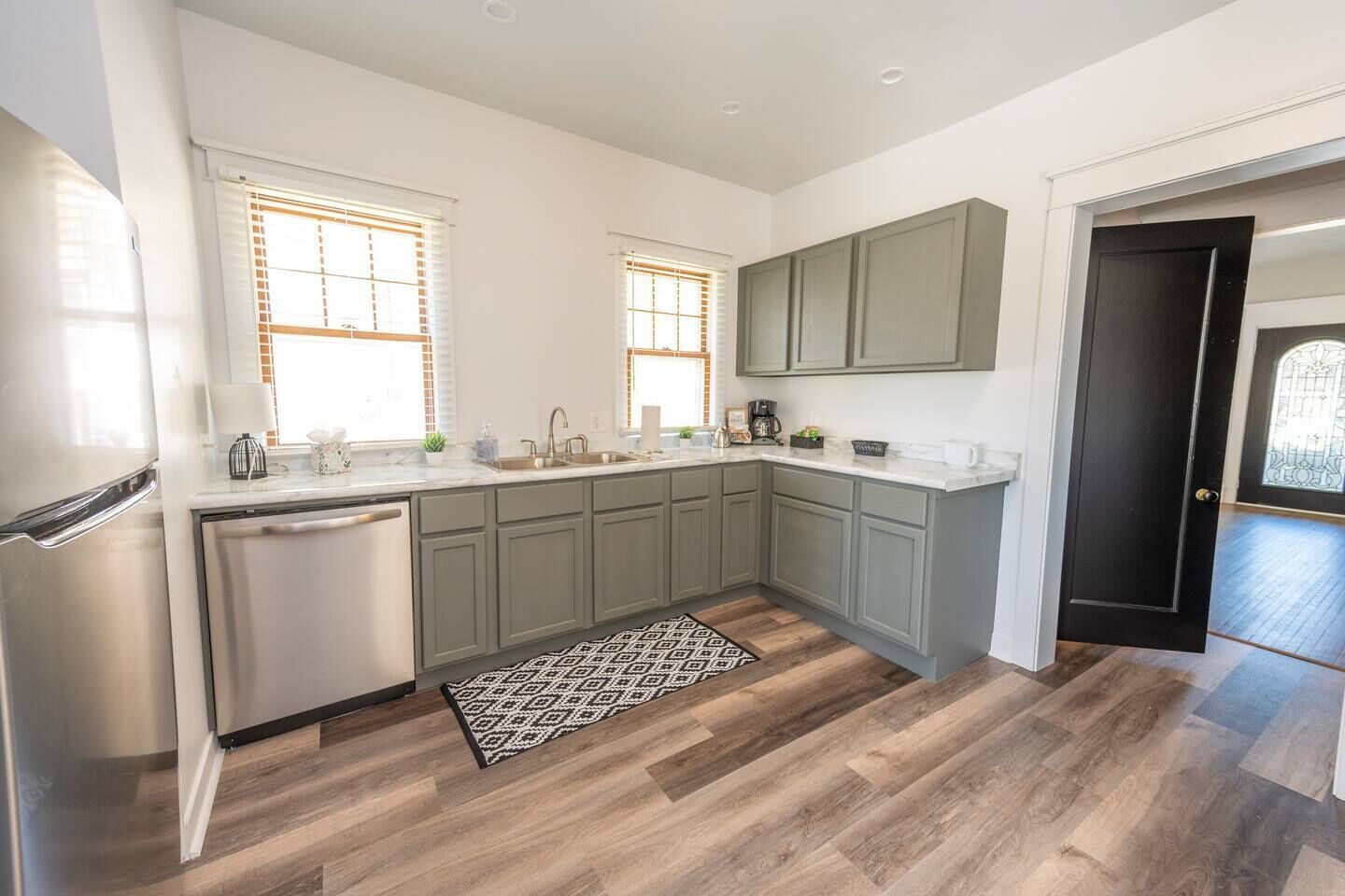 A modern kitchen with a dishwasher, double sink, and a patterned rug.