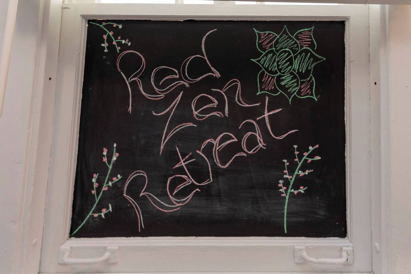 Un tableau noir sur lequel est écrit « Red Zone Retreat », entouré de dessins floraux.