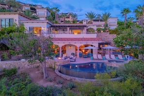 Uma casa com vários andares, piscina, área de estar ao ar livre e um pátio.