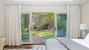 Ein Schlafzimmer mit einer großen Schiebeglastür, die zu einem Garten führt.