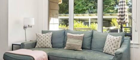 A living room with a green sofa, a round wooden coffee table, and a floor lamp.