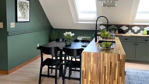 A modern kitchen with a wooden island, black chairs, and a pendant light.