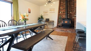 A dining area with a brick fireplace, a wooden table, and chairs. - Unleash Your Inner Explorer: The Dam Dino House! (Page)