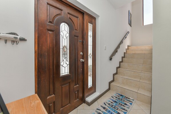 A wooden door with glass panels, a staircase with beige steps, and a patterned rug.