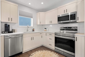 A modern kitchen with stainless steel appliances, light-colored cabinets, and a built-in dishwasher.