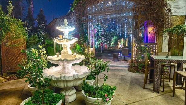 A garden with a central fountain, potted plants, and a seating area.