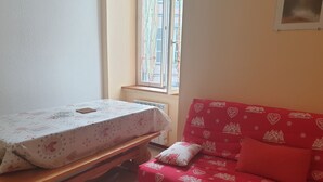 A room with a wooden bench, a red sofa with heart patterns, and a table with a floral tablecloth.