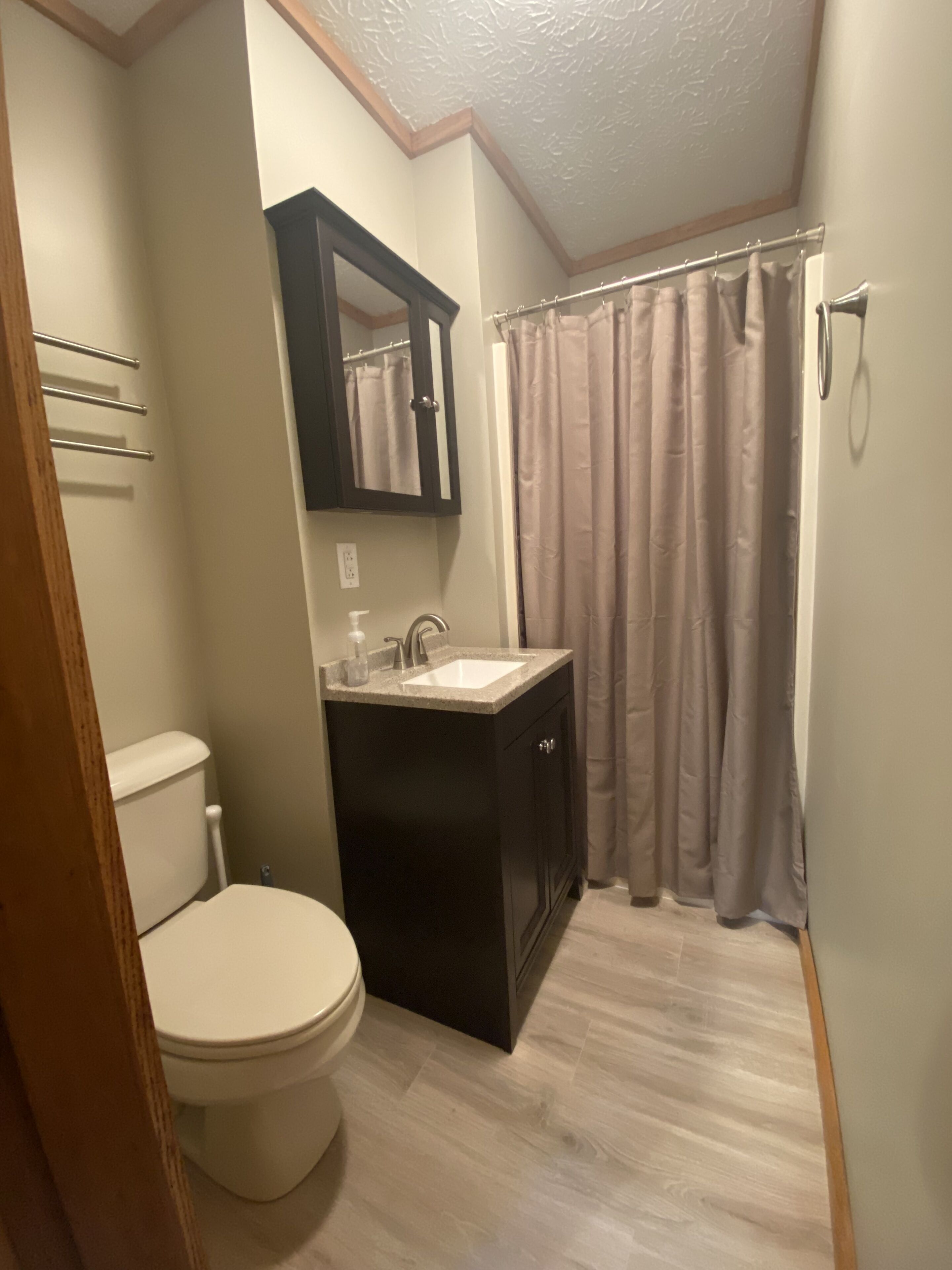 Une salle de bain équipée de toilettes, d’un lavabo, d’un miroir et d’un rideau de douche.