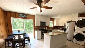 Una cocina moderna con armarios de madera, encimera de granito, ventilador de techo y un cartel que dice "THE LAKE IS MY HAPPY PLACE".