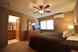 Quarto com cama, ventilador de teto, televisão e janela com persianas.