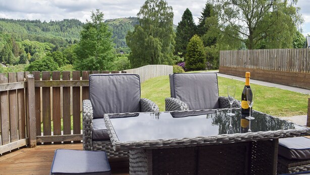 An outdoor patio with wicker furniture, a table, and a bottle of champagne. - 3 bedroom accommodation in Aberfoyle (Aberfoyle)
