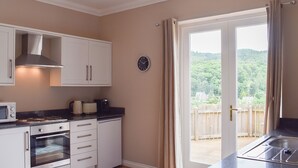 A kitchen with white cabinets, a stove, an oven, a microwave, and a clock on the wall. - 3 bedroom accommodation in Aberfoyle (Aberfoyle)