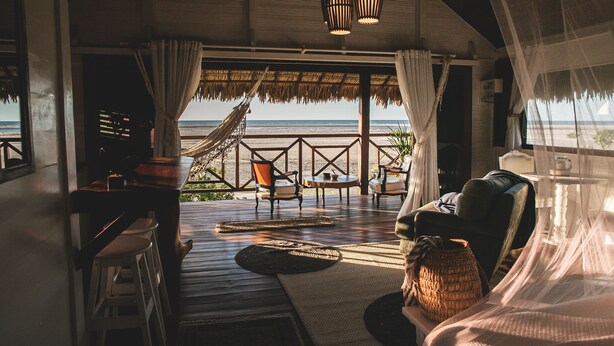 A beachside room with a hammock, a sofa, and a table. - Kitejuba Bungalows (Camocim)