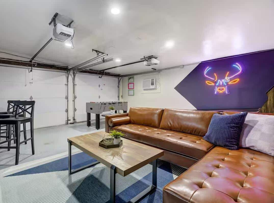 A modern interior with a leather sofa, a coffee table, and a neon sign on the wall.