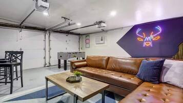 A modern interior with a leather sofa, a coffee table, and a neon sign on the wall.