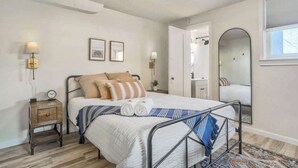 Une chambre à coucher avec un lit, des tables de chevet, un miroir et des tableaux encadrés accrochés au mur.