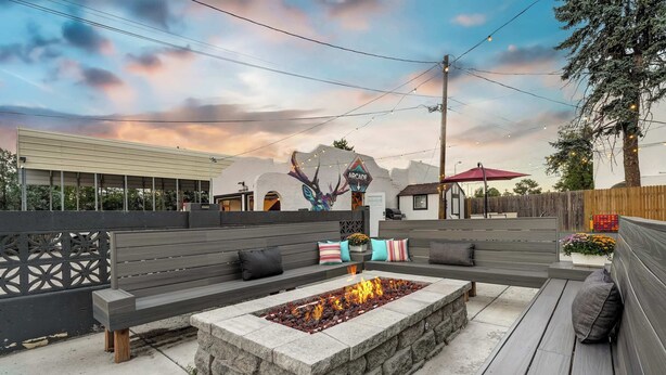 A patio with a fire pit, outdoor seating, and a mural on the wall. - Pikes Escape! Downtown Studio w/ Arcade & Firepit (Colorado Springs)