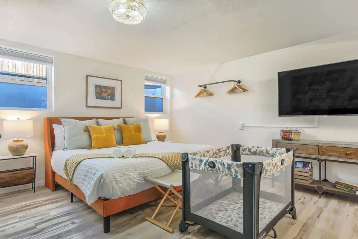 A bedroom with a bed, bedside tables, a TV, and a crib.