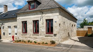 A stone building with three windows and a red fire hydrant.