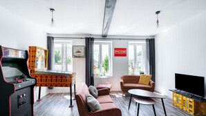 A modern living room with a retro arcade machine, a sofa, a coffee table, and a flat-screen TV.