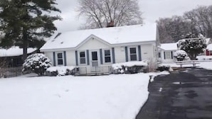 Een gelijkvloers huis met een met sneeuw bedekte sneeuwkap en voortuin.